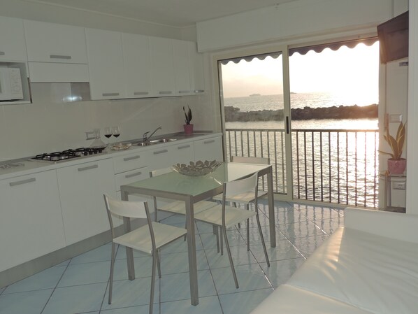 Una cocina moderna con comedor, vista al mar y un balcón con baranda.