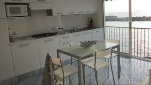 Une cuisine moderne avec des meubles blancs, un four à micro-ondes et un coin repas comprenant une table et des chaises en verre.