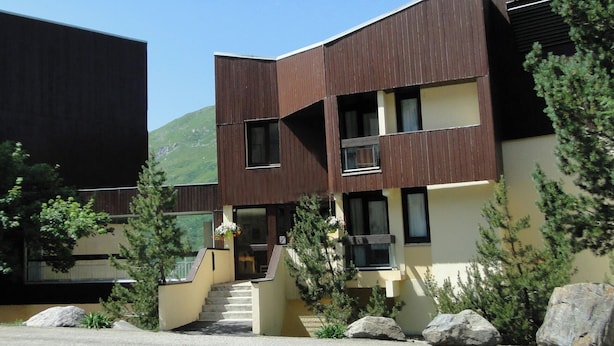 En moderne bygning med to etager, fladt tag, store vinduer og en trappe til indgangen.