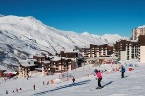 A ski resort with modern buildings, ski slopes, and a mountainous backdrop. - travelski home select - Résidence Les Lys - Studio 2 personnes Bâtiment A (Les Menuires)