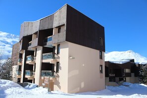 A multi-story building with a modern architectural design, featuring balconies and large windows. - travelski home select - Résidence Les Lys - Studio 2 personnes Bâtiment A (Les Menuires)