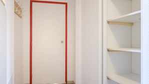 A hallway with a white door, wooden flooring, and white shelving units. - travelski home select - Résidence Les Lys - Studio 2 personnes Bâtiment B (Les Menuires)