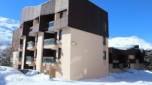 Ein mehrstöckiges Gebäude mit moderner Architektur, das Balkone und große Fenster aufweist.