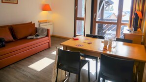 Una habitación acogedora con una mesa de comedor de madera, un sofá rojo y una lámpara.