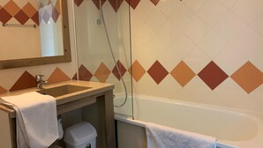 Baño con lavamanos, espejo y ducha.