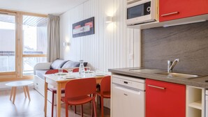 Une cuisine moderne équipée d’un four à micro-ondes, d’un évier et d’un lave-vaisselle. Un coin repas avec une table et des chaises est également à disposition.