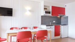 Une cuisine de taille réduite, équipée d’un four à micro-ondes, d’une cuisinière et de placards rouges.