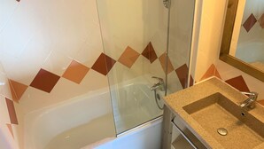 Ein Badezimmer mit einer Duschkabine, einer weißen Badewanne und einem Waschbecken mit Granitplatte.