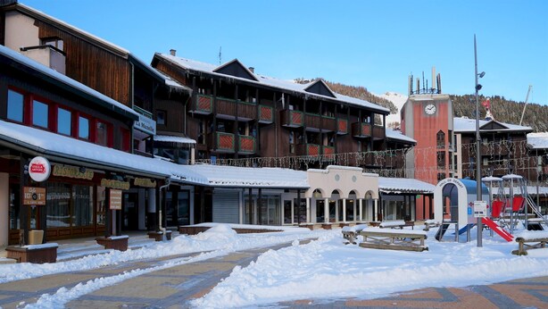 Ein verschneiter Platz mit Gebäuden, darunter ein Restaurant und ein Hotel.