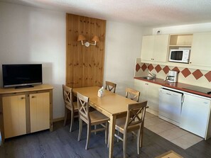 A compact kitchen with a dining area, wooden cabinets, a microwave, and a coffee maker.