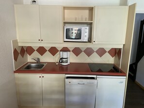 Eine kleine Küche mit Mikrowelle, Kaffeemaschine, Spüle und Geschirrspüler.
