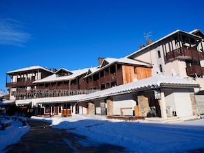 A multi-story hotel with balconies, a ski lift, and a snow-covered ground.