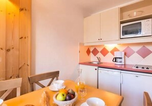 Une cuisine équipée d’un four à micro-ondes, d’une machine à café et d’un panier à fruits posé sur le plan de travail.