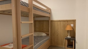 Quarto com beliche, escrivaninha e luminária.