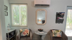 A cozy room with two armchairs, a small table, a mirror, and a bookshelf.