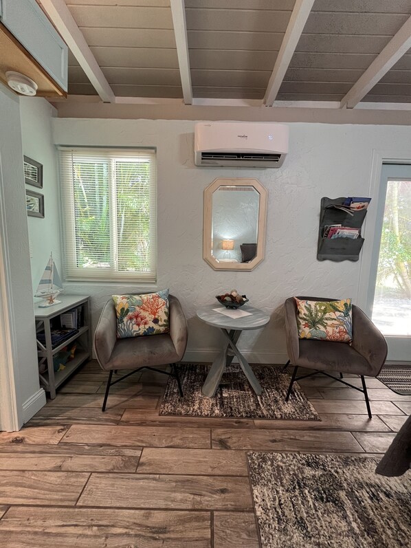 Una habitación acogedora con dos sillones, una mesita, un espejo y una estantería.