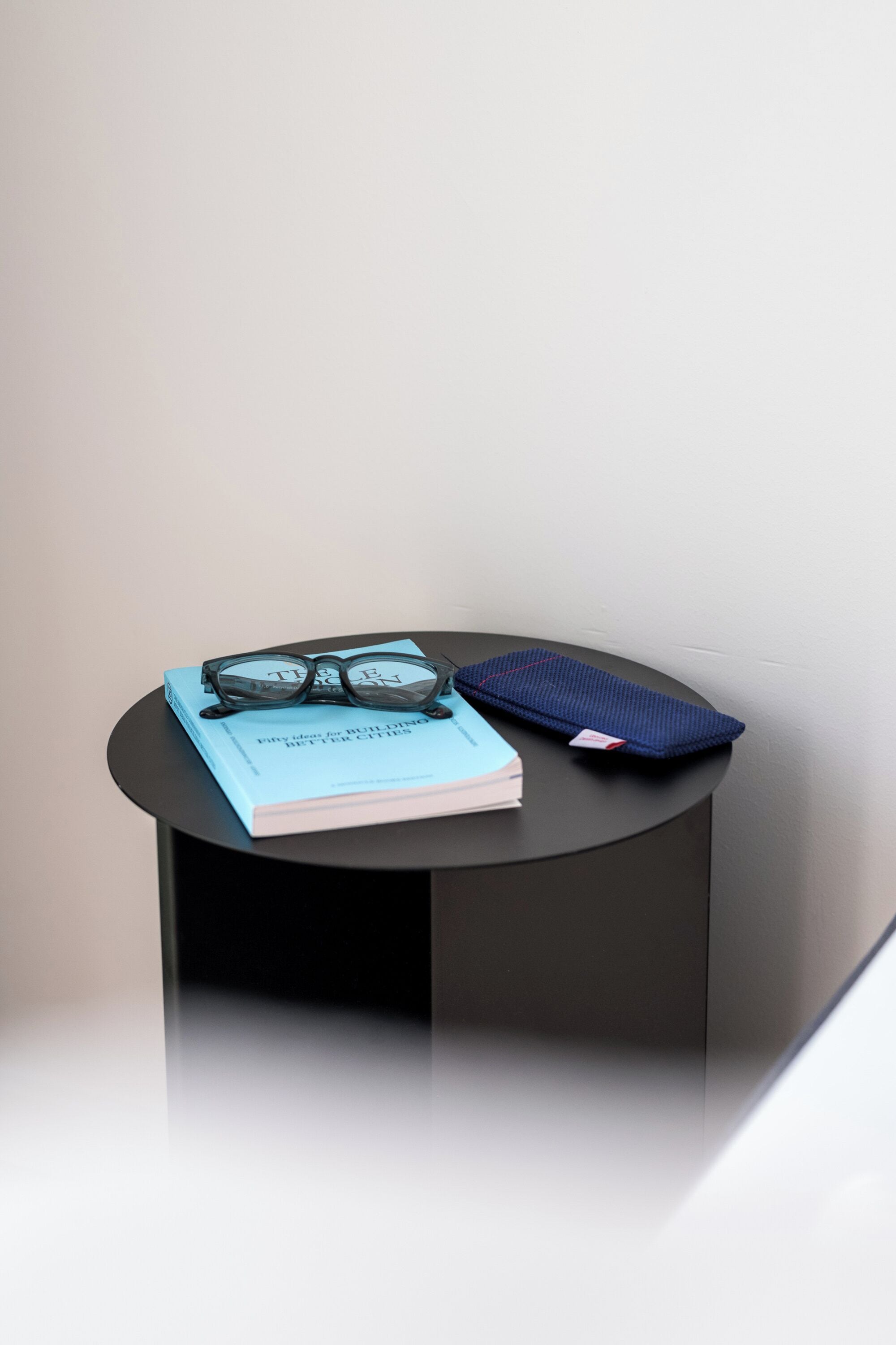 A small round table with a book, glasses, and a notebook.
