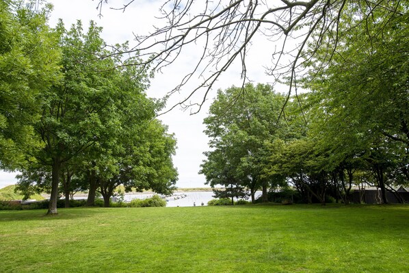 A grassy park area with trees and a view of a body of water. - The Beach Gardens - Daniel&Jacob's Premium Apartments (Copenhagen)
