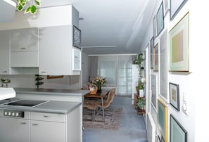 A modern kitchen with a built-in stove, white cabinetry, and a dining area with a wooden table and chairs.
