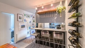 Eine moderne Küche mit Bar, Weinkühlschränken und gerahmten Bildern an der Wand.