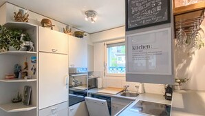 Eine moderne Küche mit weißen Schränken, einem Geschirrspüler, einer Spüle und einem Fenster für natürliches Licht.