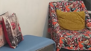 Een kamer met een blauwe bank en een gestreept fauteuil met een geel kussen.