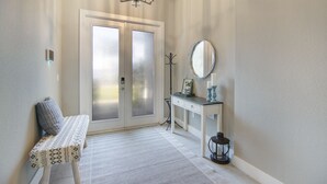 A hallway with a bench, a desk, a mirror, and a chandelier. - Amazing Outdoor kitchen & Private Screened In Pool (Bonita Springs)