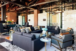 A modern living room with a sectional sofa, a coffee table, and a patterned rug. - Archer Hotel Tysons (McLean)