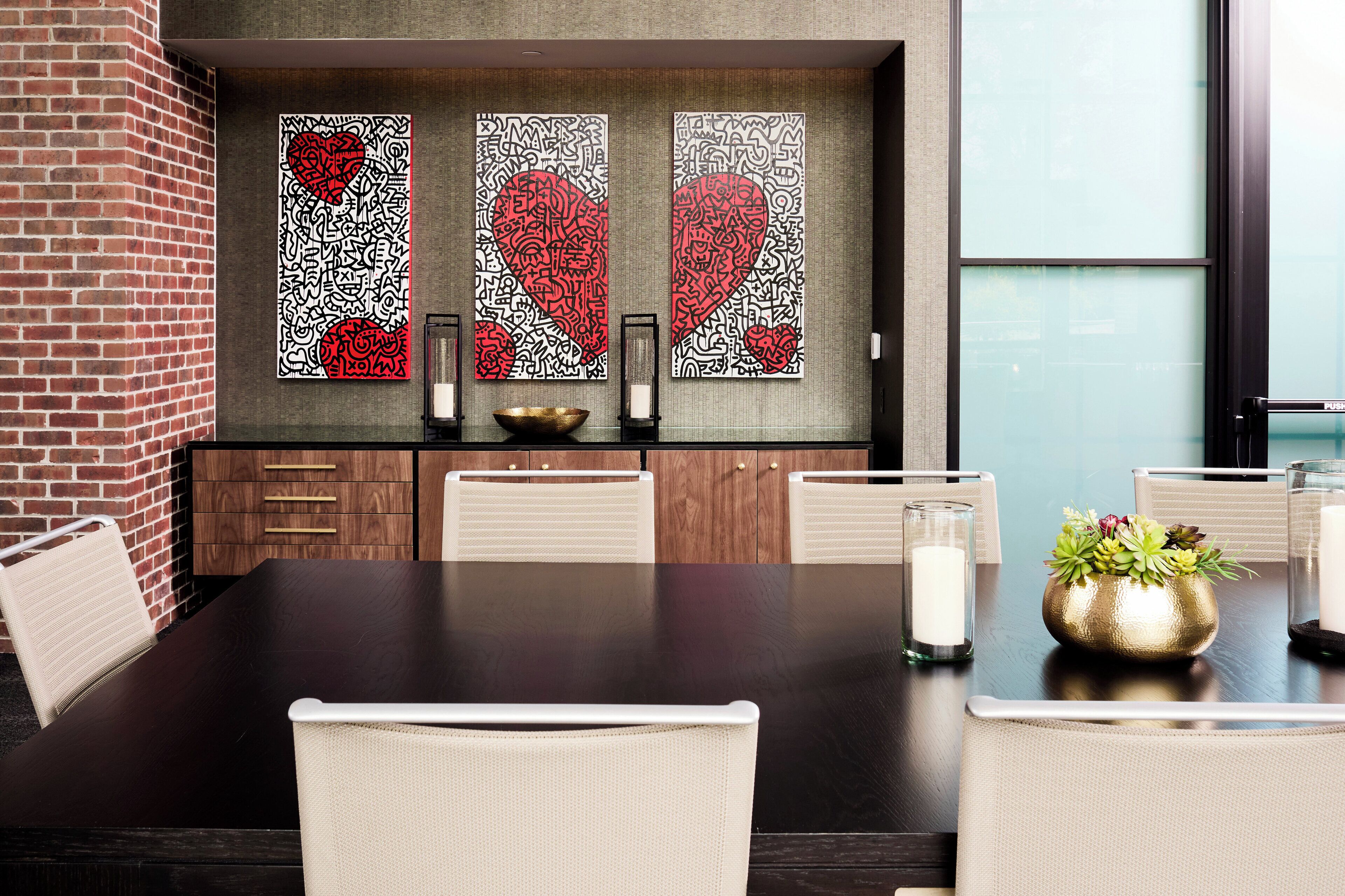 A conference room with a dark wooden table, white chairs, and decorative wall art featuring hearts.