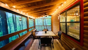 A cozy cabin with a wooden interior, a dining table with chairs, and large windows offering a view of the forest. - ★Cozy Log Cabin★ Secluded, modern amenities, mins to dwtwn Blueridge. Pets OK! (Blue Ridge)