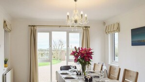 A dining room with a table set for four, a chandelier, and a view of the outdoors.