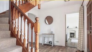 A staircase with wooden balusters leading to a landing with a white console table and a mirror.
