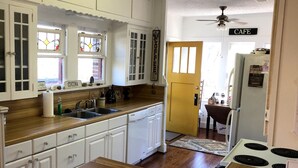 Una cocina con armarios blancos, encimera de madera, un lavamanos y una estufa.