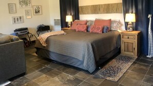 Un dormitorio con una cama grande, dos mesitas de noche con lámparas, un aparador, una silla y una alfombra.