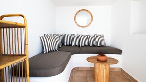 Une pièce moderne et compacte, dotée d’un canapé d’angle aux lignes courbes, d’une petite table en bois et d’une chaise en bambou.