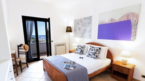 Une chambre à coucher comprenant un lit, une chaise, une table de chevet, une lampe et une vue sur l’extérieur.