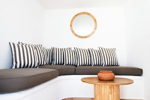 Una sala de estar moderna con un sofá modular, una mesa de centro redonda de madera y un espejo circular en la pared.