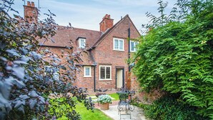 A brick house with a small garden, a patio with a table and chairs, and a hedge. - 2 bedroom accommodation in Preston Crowmarsh, near Wallingford (Preston Crowmarsh, near Wallingford)