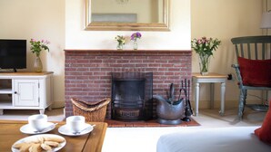 A cozy living room with a fireplace, a television, and a dining area with a table set for two. - 2 bedroom accommodation in Preston Crowmarsh, near Wallingford (Preston Crowmarsh, near Wallingford)