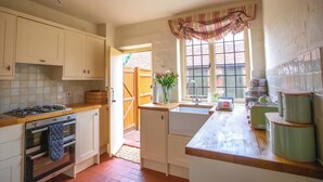 A kitchen with white cabinets, a gas stove, an oven, a sink, and a window with a curtain. - 2 bedroom accommodation in Preston Crowmarsh, near Wallingford (Preston Crowmarsh, near Wallingford)