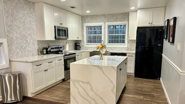 A modern kitchen with white cabinetry, a central island, a black refrigerator, and a microwave above the island. - Sleeps 10! Brand new kitchen & main bathroom! Highly sought after 4bd,3ba. (Smyrna)