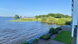 Vista al río con un espacio verde y un edificio junto al agua.