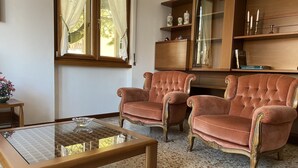 Un salon comprenant deux fauteuils confortables, une table basse en verre et un meuble en bois orné d’objets décoratifs.