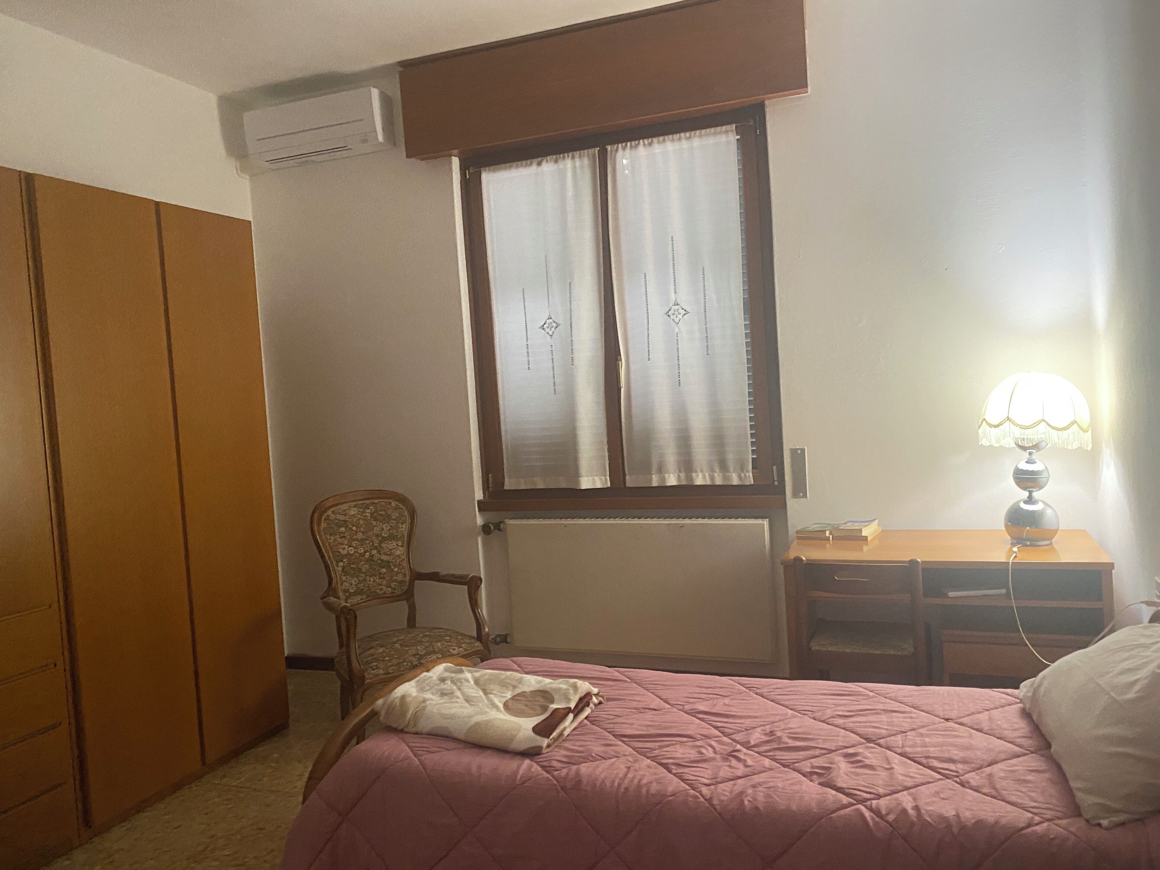 Une chambre à coucher avec un lit, une chaise, un bureau et une lampe.