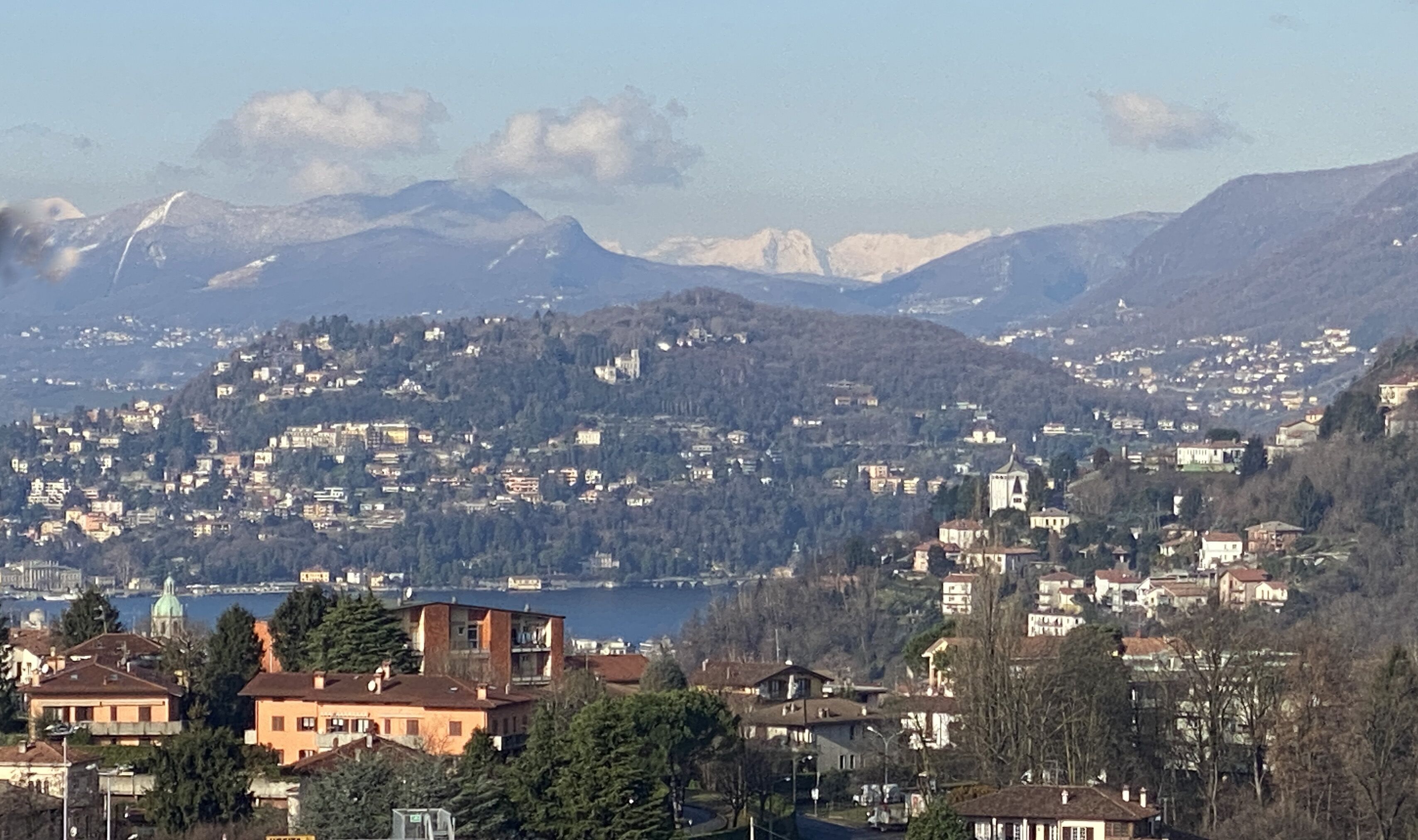 Une ville où se côtoient des immeubles d’habitation et une église imposante, le tout sur fond de montagnes.