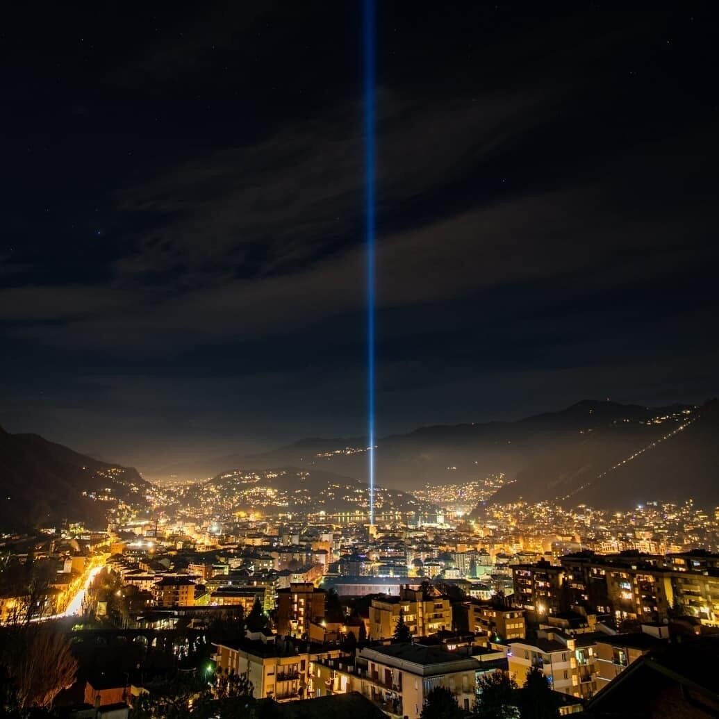 Paesaggio urbano notturno con un fascio di luce verticale ben visibile.