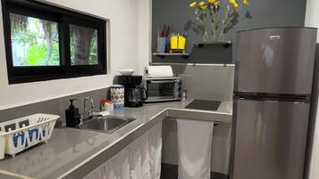 A modern kitchen with a built-in oven, a refrigerator, and a window overlooking greenery.
