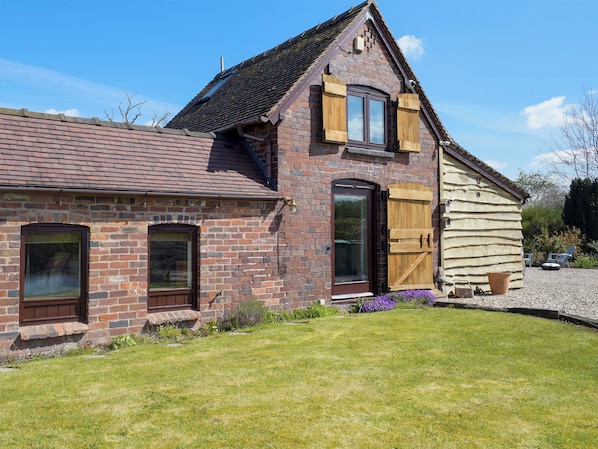 A brick house with a sloped roof, a large window, and a wooden door.