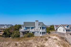 A coastal house with a balcony, a deck, and a view of the beach.