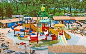 Parque acuático con diversas toboganes y estructuras de juego, rodeado de sombrillas y sillas reclinables.